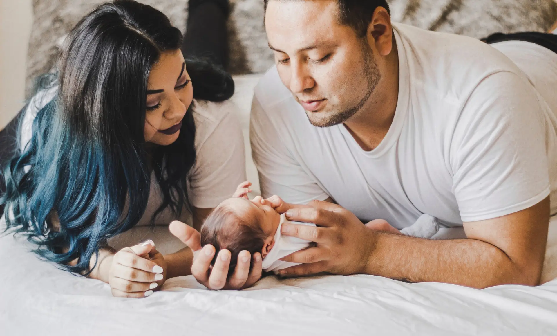 Ouders liggen samen met hun pasgeboren baby op bed